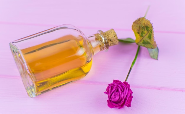 Una botella con un elixir amarillo sobre un fondo de madera rosa.