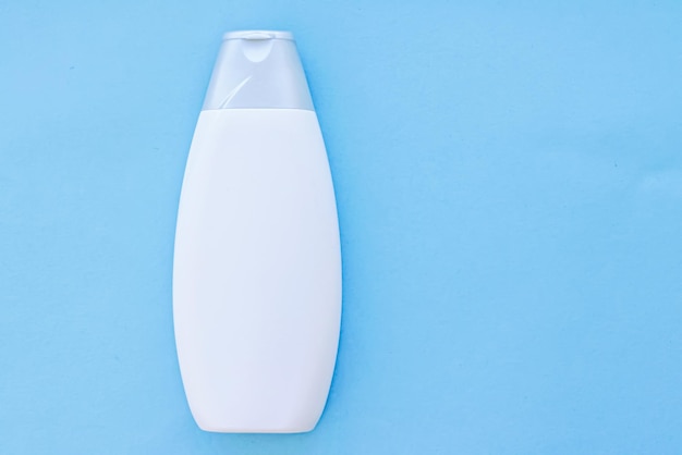 Botella de envase cosmético de etiqueta en blanco como maqueta de producto sobre fondo azul