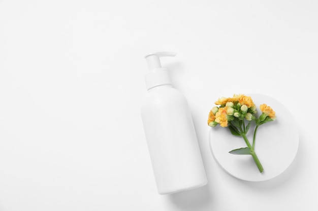 Botella de flores de productos cosméticos y podio sobre fondo blanco plano Espacio para texto