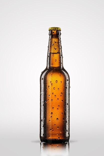 Botella fría de cerveza con gotas aisladas sobre fondo gris.