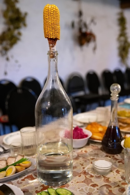 Botella grande de vodka con mazorca de maíz como tapón de un primer plano de botella