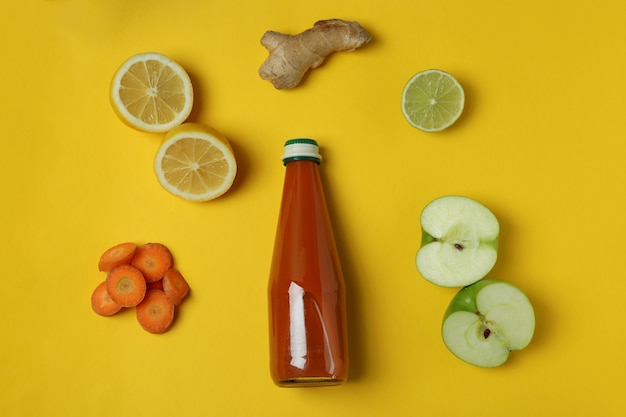 Botella de jugo e ingredientes sobre fondo amarillo aislado