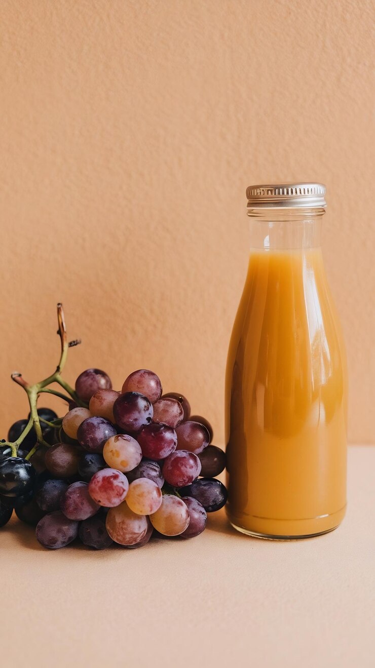 Foto una botella de jugo de naranja al lado de un racimo de uvas