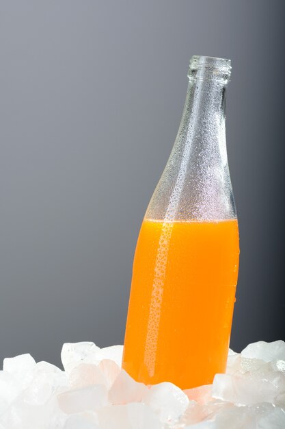 Foto la botella de jugo de naranja con hielo.