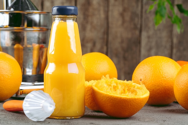 Botella de jugo de naranja con naranjas en mesa de madera