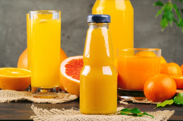 Botella de jugo de naranja con naranjas en mesa de madera