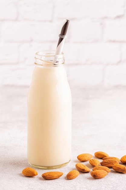 Una botella de leche de almendras y almendras sobre un fondo claro.