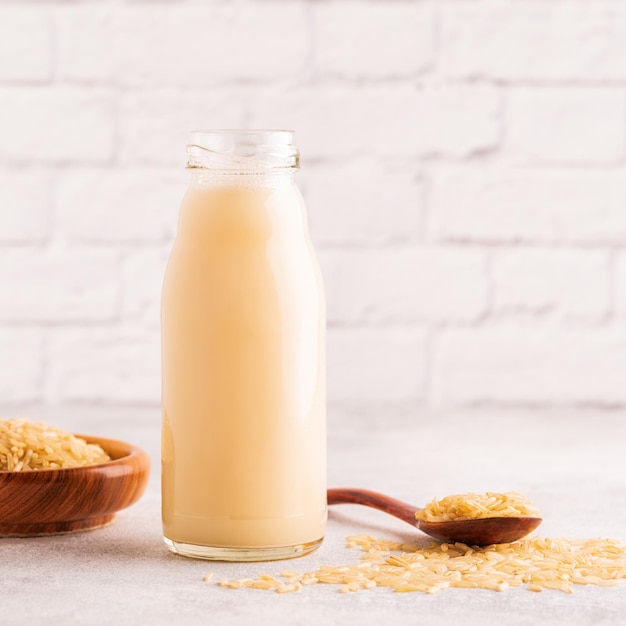 Una botella de leche de arroz y arroz sobre un fondo claro.