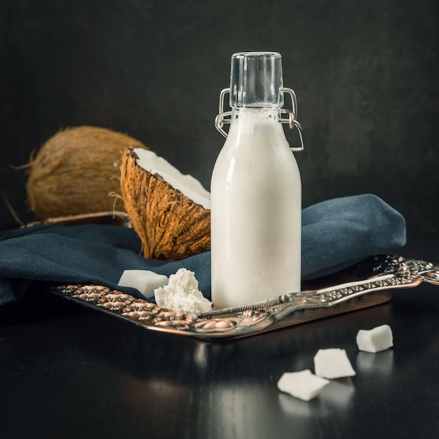 Botella de leche de coco y coco sobre un fondo negro Alternativa saludable sin lácteos