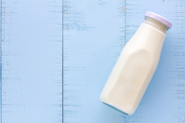 Una botella de leche en el fondo de madera azul.