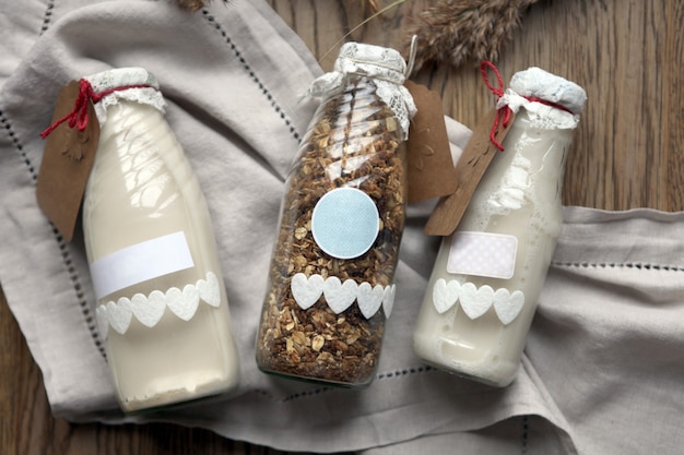 Botella de leche fresca con copos de avena y granos de trigo integral en la mesa de madera. Muesli o yogur o leche de granola casera sobre fondo de madera rústica
