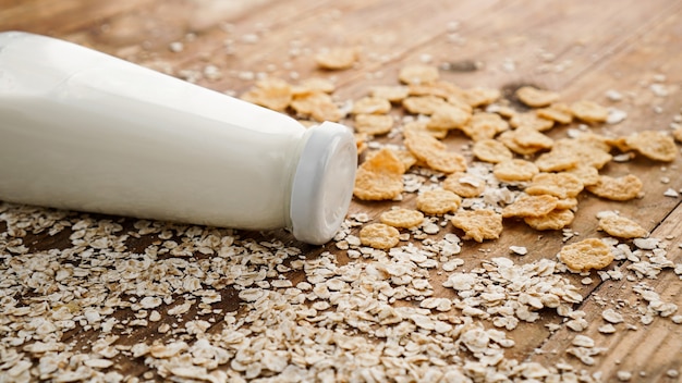 Botella de leche fresca sobre superficie de madera con avena y cereales. Concepto de comida sana y natural.