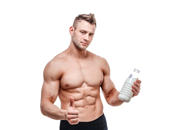 Una botella de leche en la mano, un hombre de cuerpo deportivo posando sobre una pared blanca.