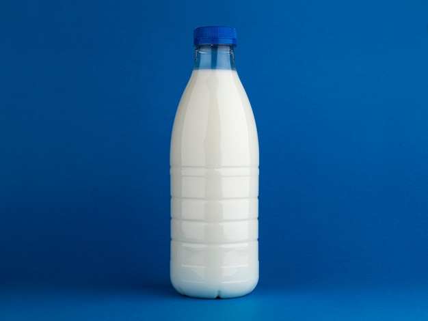 Botella de leche simulacro aislado sobre fondo azul.