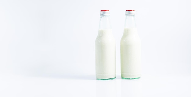 botella de leche sobre un fondo blancoLeche fresca en una botella de vidrio y vacía aislada sobre fondo blanco