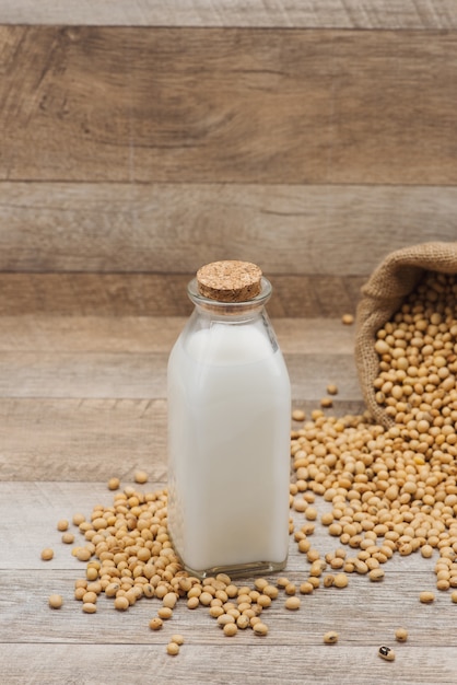 Botella de leche de soja y soja en mesa de madera