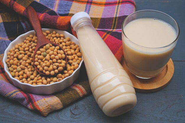 Botella de leche de soja y soja en mesa de madera