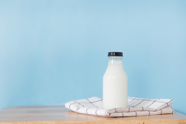 botella de leche y un vaso sobre una mesa de madera.