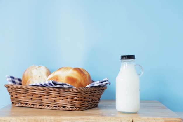 botella de leche y un vaso sobre una mesa de madera.