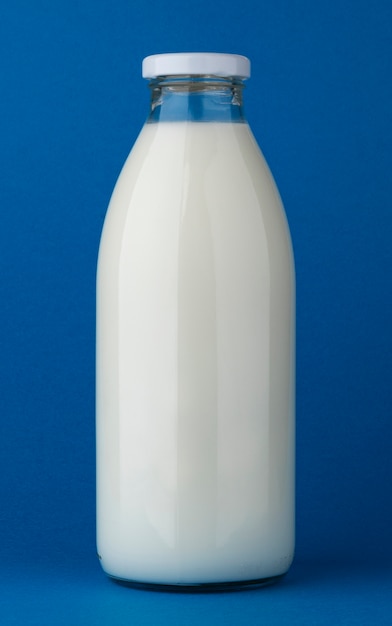 Botella de leche de vidrio simulacro sobre fondo azul.