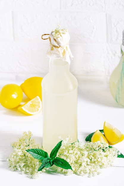 Botella de limonada de jugo cordial de flor de saúco orgánica saludable casera con flores de saúco frescas e ingredientes frescos para una bebida saludable y refrescante.