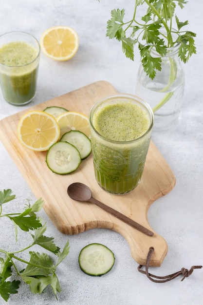 Botella de limonada y un vaso servido con rodajas de limón y pepino sobre un fondo claro Copiar espacio