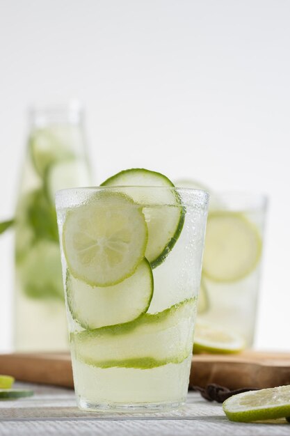 Botella de limonada y un vaso servido con rodajas de limón y pepino sobre un fondo claro Copiar espacio