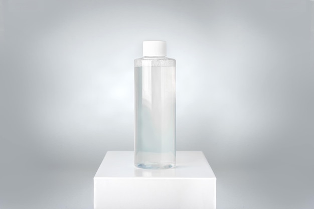 Botella limpia de agua micelar en pedestal blanco
