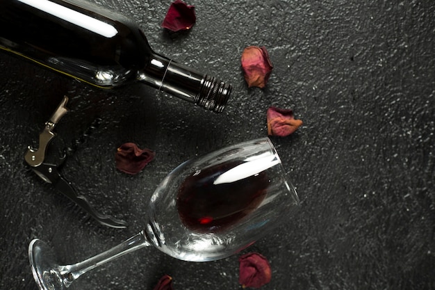 Botella llena de vino tinto y vaso vacío sobre la mesa