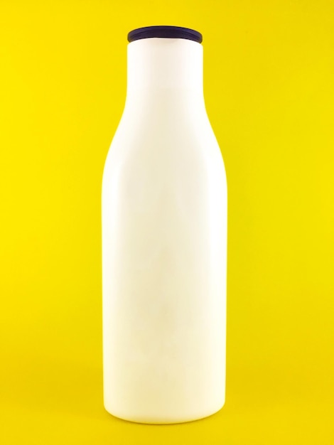 botella de loción de belleza blanca sin etiqueta sobre un fondo amarillo