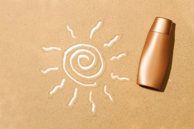 Una botella de loción bronceadora y un dibujo del sol en la arena.