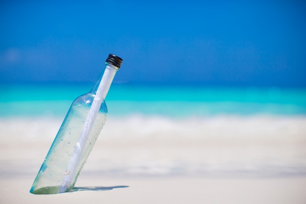 Botella con un mensaje enterrado en la arena blanca