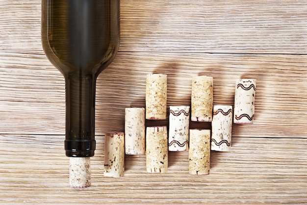 Botella oscura de vino con los corchos en la tabla de madera con el espacio de la copia.