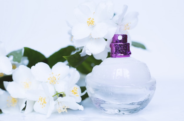 Botella de perfume con aroma de flores sobre superficie blanca