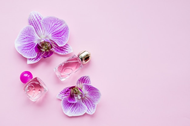 Botella de perfume femenino y delicadas flores de orquídeas