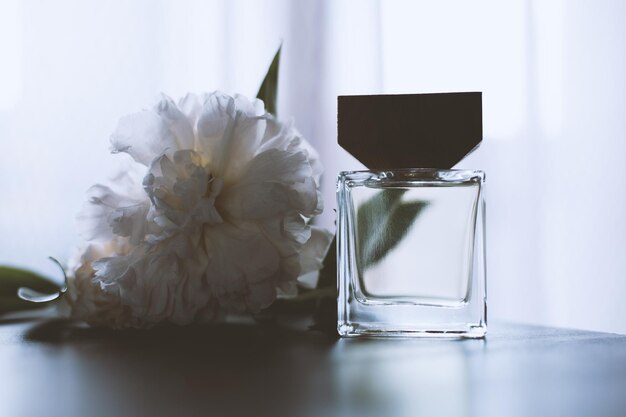 Botella de perfume con flores blancas.