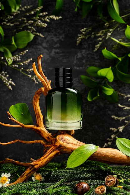 Una botella de perfume con hojas verdes en una rama.
