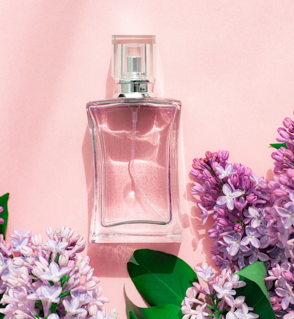 una botella de perfume y lila sobre una superficie rosa perfume de mujer