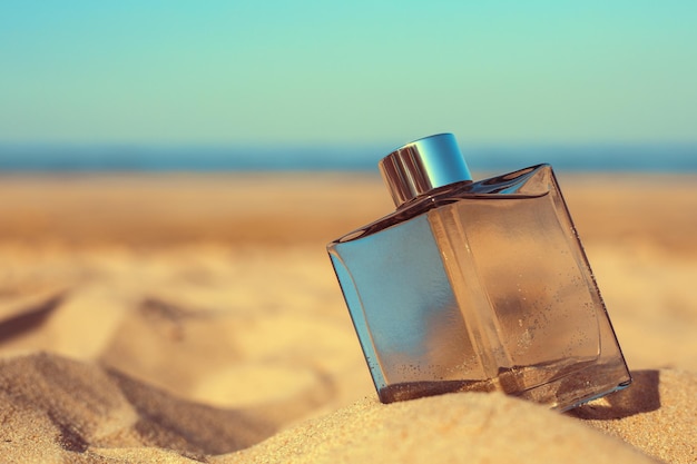 Foto botella de perfume en la playa contra el fondo del mar