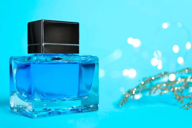 Botella de perfume sobre fondo azul claro con luces borrosas de primer plano Espacio para el texto