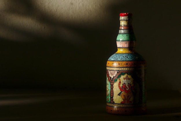 Botella pintada con Ganesha en el estilo tradicional indio de pattachitra contra un fondo oscuro