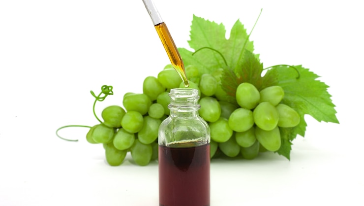 Foto botella con pipeta con aceite de semilla de uva verde sobre fondo blanco.