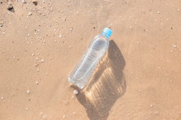 Botella de plástico con agua en una playa de arena Vista superior plana