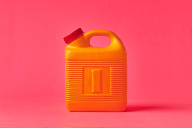 Foto botella de plástico amarilla sobre fondo rosa utilizada para almacenar mezcal en méxico
