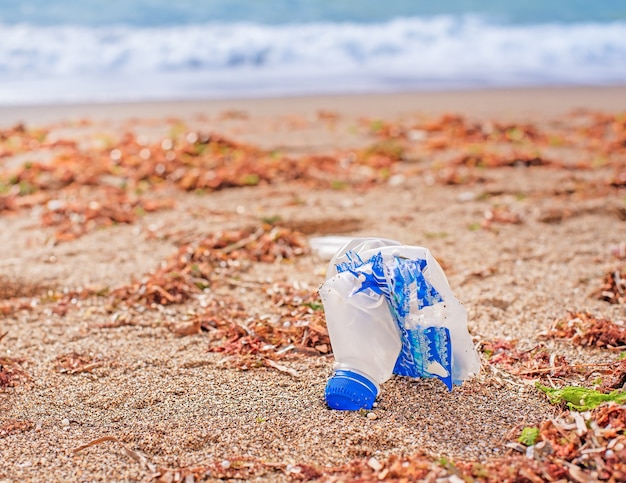 Una botella de plástico arrojada por una ola a la contaminación de la playa en el océano