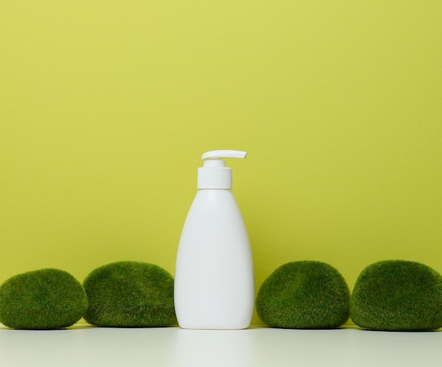 Foto botella de plástico blanco con bomba sobre un fondo verde envases para cosméticos