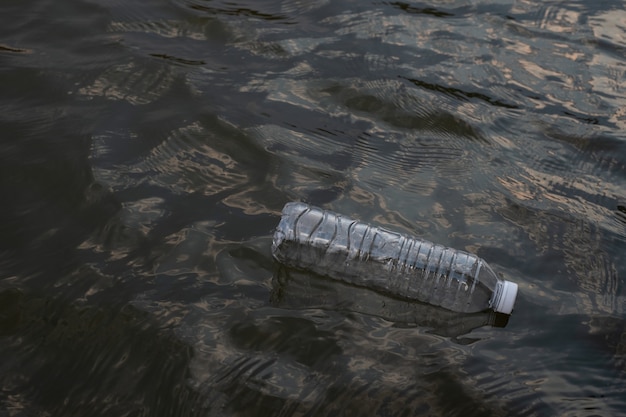 Foto botella de plástico de desecho usado flotando en el agua en un canal