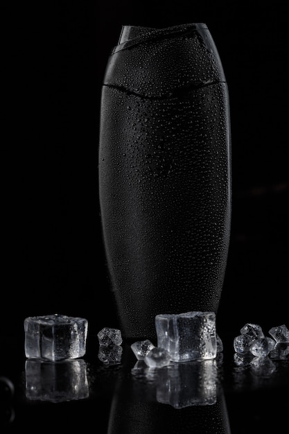 Botella de plástico negra para champú con cubitos de hielo.