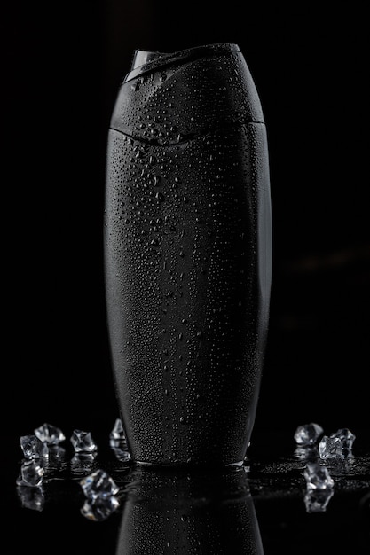 Botella de plástico negra para champú con cubitos de hielo.