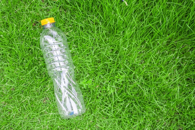 Botella de plástico sobre fondo de hierba verde reciclar y concepto de contaminación